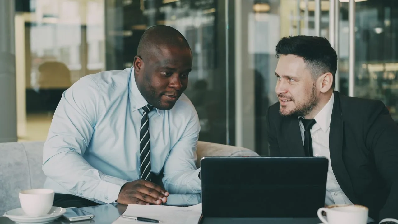 Two professionals reviewing employee benefits on a laptop